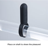 Black ring-like device with an attached vertical handle, placed around a clear cylindrical object on a white background. Text below the image reads, "Place on the shaft to share the pleasure!" Experience a new level of intimacy with the Tenga TENGA SVR Smart Vibe Vibrating Ring's comfortable silicone fit.